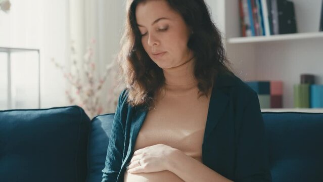 Nervous middle-aged pregnant woman touching belly and deeply breathing, anxiety