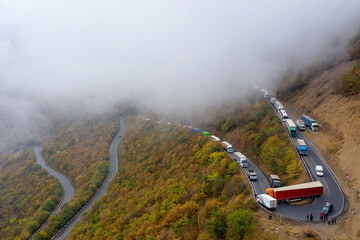 Drone view of traffic jam on hairpin turn on foggy autumn morning. Tatev, Syunik Province, Armenia.