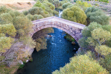 Fototapeta premium Drone view of medieval Dadal bridge across Arpa river on autumn evening. Yeghegnadzor, Vayots Dzor Province, Armenia.