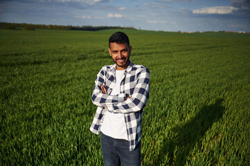 Naklejka na ściany i meble Standing with arms crossed. Handsome Indian man is on the agricultural field