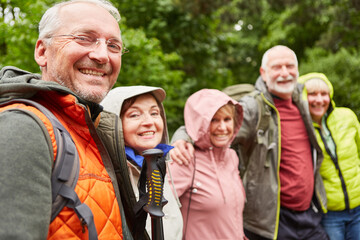 Happy elderly male and female friends hiking in forest