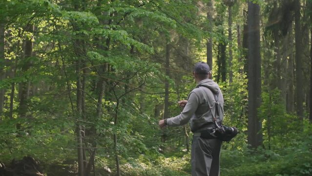 Fisherman catching brown trout on the fly standing in river. Slow motion. 