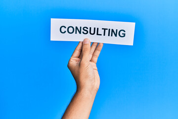 Hand of caucasian man holding paper with consulting word over isolated blue background