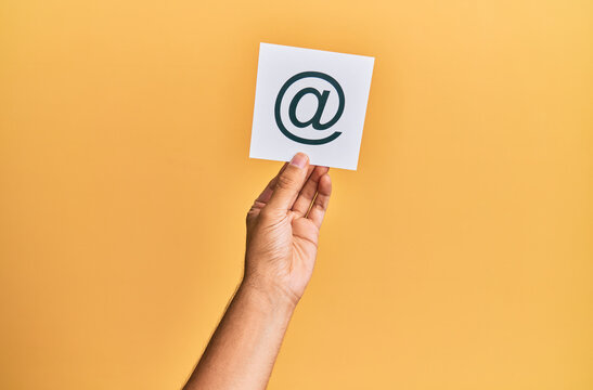 Hand of caucasian man holding paper with @ message over isolated white background