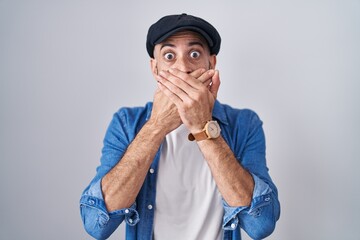 Hispanic man with beard standing over isolated background shocked covering mouth with hands for...