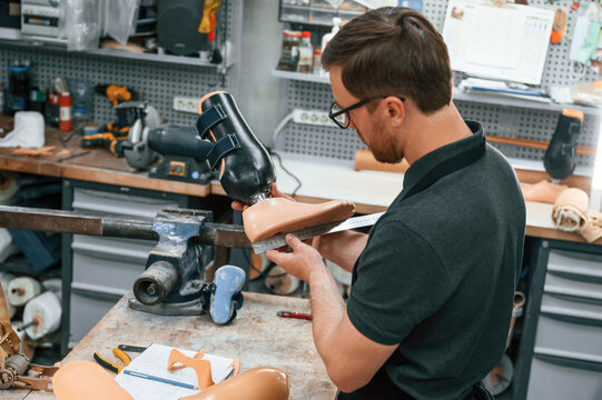 Standing, checking measure of the prosthesis. Technician working in modern laboratory