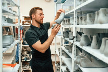 Shelves with shoes. Technician working indoors - Powered by Adobe