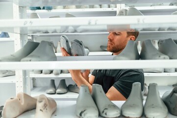 Choosing raw shoe for the prosthesis on the shelves. Technician working in modern laboratory