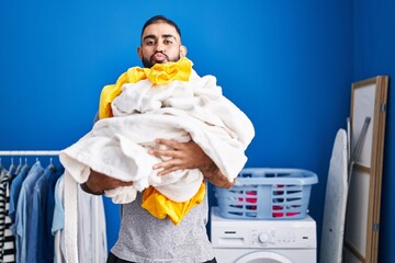 Middle east man with beard holding pile of laundry looking at the camera blowing a kiss being lovely and sexy. love expression.