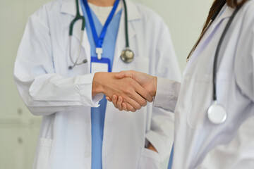 Close up shot of two doctors shaking hands to each other. Healthcare, collaboration in medicine and teamwork