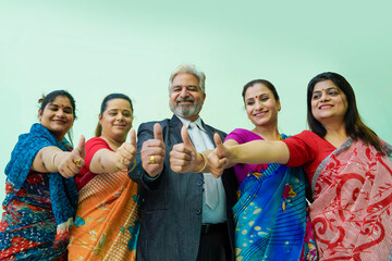 Senior businessman with women employee group showing thumps up.