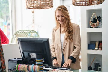 Young blonde woman shop assistant smiling confident working at clothing store