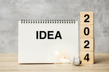 2024 text wood cube blocks and IDEAS word with lightbulb on table. New Year New Ideas, Creative, Innovation, Imagination, inspiration, Resolution, Strategy and goal concept