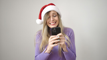 Young blonde woman wearing christmas hat using smartphone over isolated white background