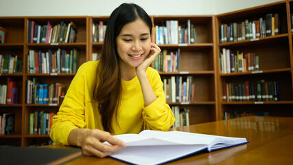 Pleased female student reading book in a library for studying and research. Education, learning, knowledge and university