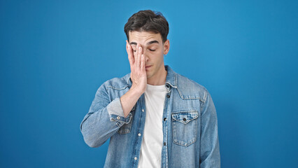 Obraz premium Young hispanic man stressed standing over isolated blue background