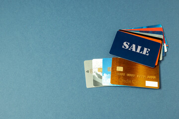 Credit cards of different issuers, SALE card, sale cards in a fan lie on a blue background. Pile of credit cards for different purposes