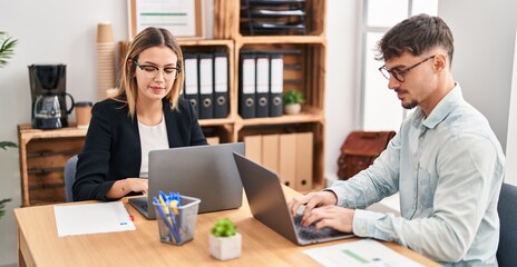 Young man and woman business workers using laptop working at office