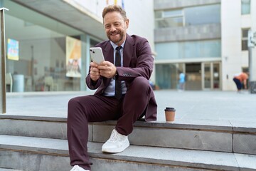Middle age man business worker using smartphone sitting on stairs at street