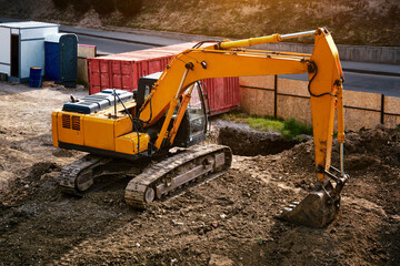 Top view of a modern excavator digs the ground at a construction site in the city.