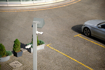 Top view surveillance camera in an open parking lot near a hotel.