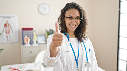 Young beautiful hispanic woman doctor doing thumb up at clinic