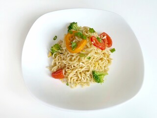 Instant noodles with vegetables and herbs in white plate 