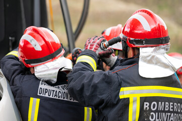Fototapeta premium Firefighters using hydraulic tools during a rescue operation training. Rescuers unlock the passenger in car after accident. High quality photography.