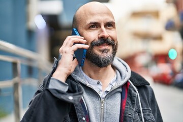 Young bald man smiling confident talking on the smartphone at street