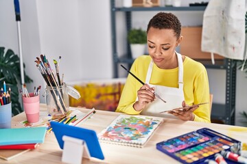African american woman artist using touchpad drawing on notebook at art studio