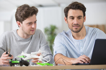 two men are getting online help to assemble a drone