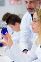 Science student looking at liquid in erlenmeyer flask
