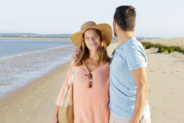 couple walking on beach man looking back over his shoulder