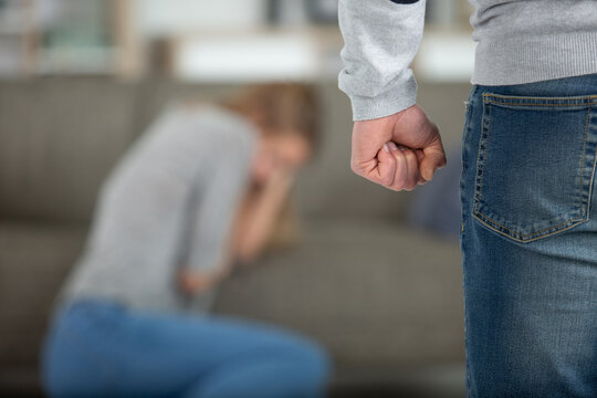 Woman Coweing Behind Man With Clenched Fist