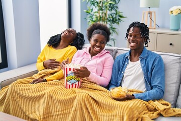 African american friends watching movie sitting on sofa at home