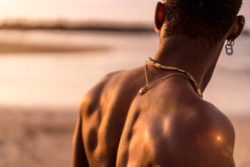 Fototapeta na wymiar Back of muscular black ethnic man on summer vacation by the sea feeling free
