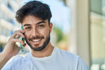 Young hispanic man smiling confident talking on the smartphone at street