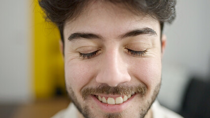 Fototapeta premium Young hispanic man smiling confident sitting on sofa at home