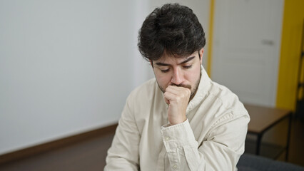 Fototapeta na wymiar Young hispanic man stressed sitting on sofa at home