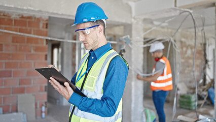 Two men builders writing document working at construction site