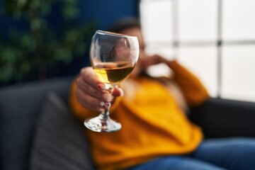 Young beautiful plus size woman drinking wine sitting on sofa at home
