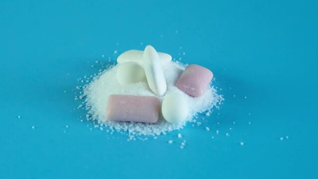 Chewing gum and tooth-friendly sweets with xylitol on slide of crystalline xylitol powder. Video, rotational movement. Concept - dental health. Sugar substitute, Xylit. Food additive, E967.