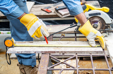 Fototapeta premium Construction worker are using tape measurements to measure planks and pencil are used to write, Close up of male hands measuring wood flooring, Construction industry, housework do it yourself..
