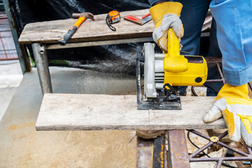 Carpenter using circular saw for cutting wooden boards with power tools, construction and home renovation, repair and construction tool