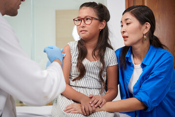 Girl almost crying when doctor injecting vaccine in her forearm