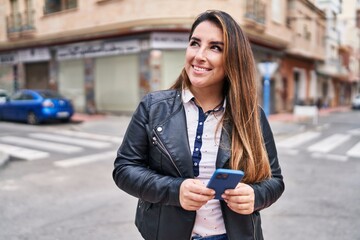 Young beautiful hispanic woman smiling confident using smartphone at street