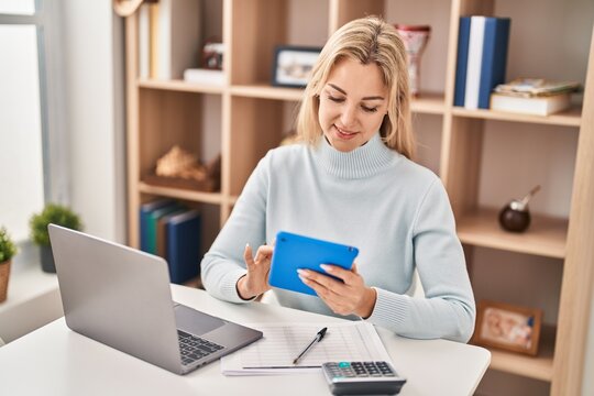 Young blonde woman using laptop and touchpad at home