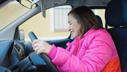 Fototapeta na wymiar Mature hispanic woman with grey hair smiling confident driving car at street