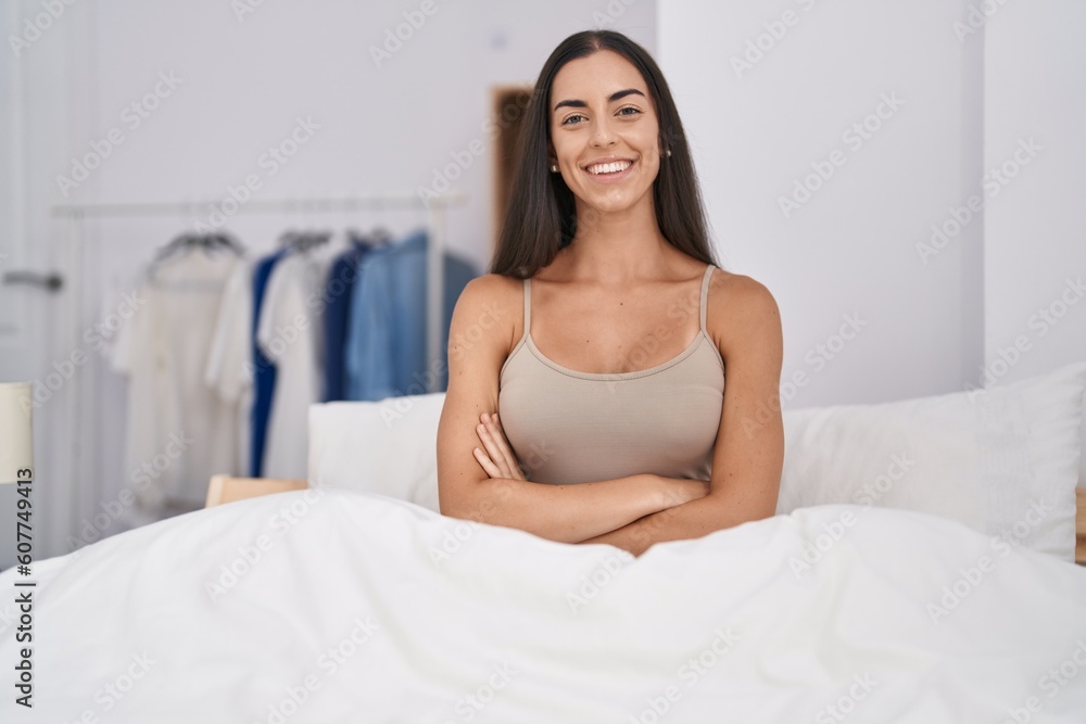 Poster young brunette woman in the bed at home happy face smiling with crossed arms looking at the camera. 