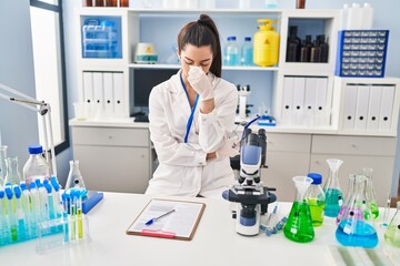 Young beautiful hispanic woman scientist stressed working at laboratory